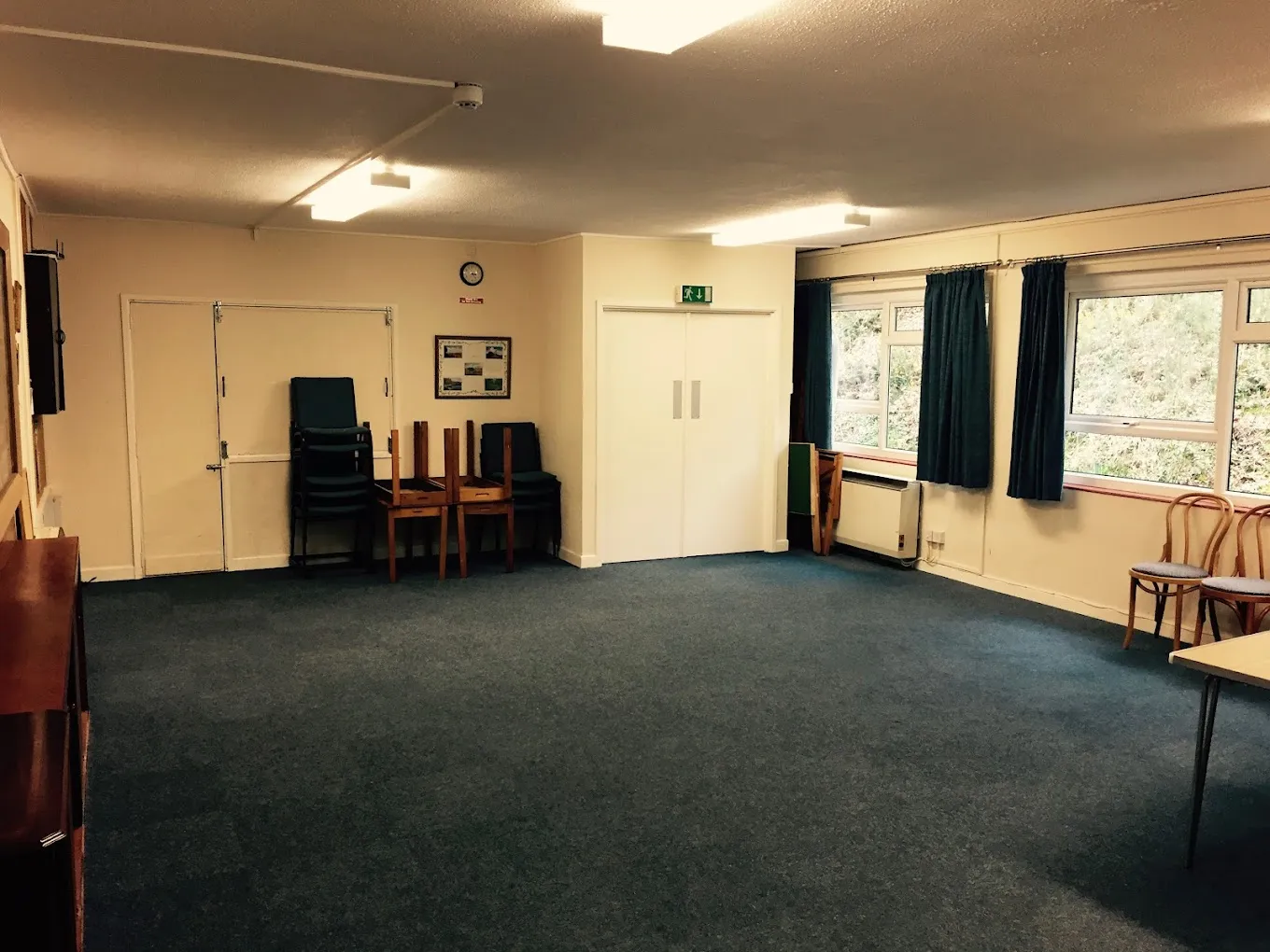 Meeting Room interior — neutral carpeted room with large windows and stacked chairs